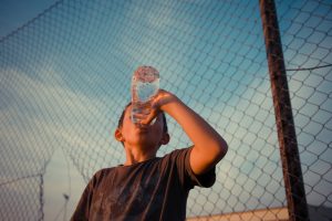 Kid drink water by a fence