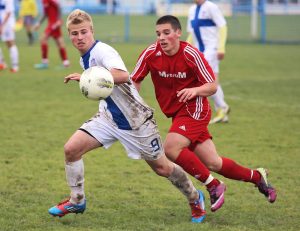 Two opposing team players racing for soccer ball